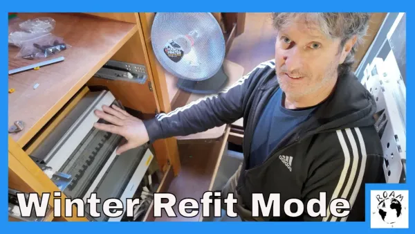 AC electrical panel with breakers and waterproof cable glands installed during catamaran refit in cold weather.